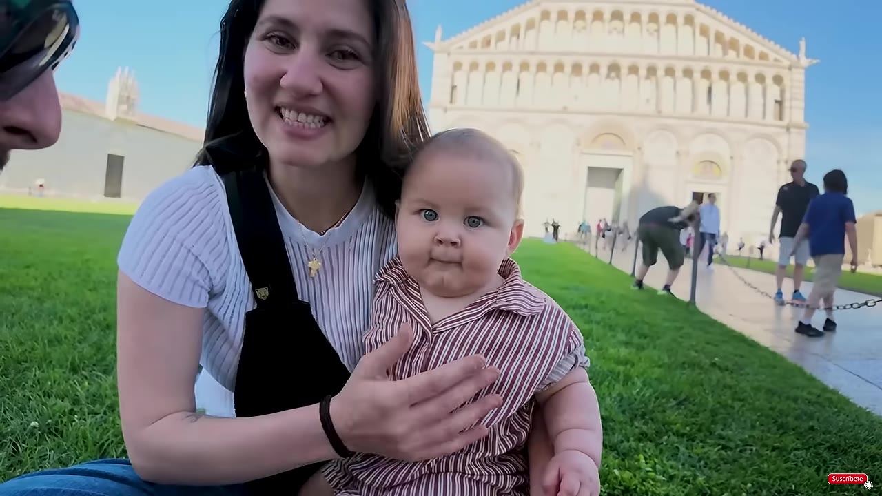 Visitors walking beside Pisa Cathedral and the Baptistery in Piazza dei Miracoli